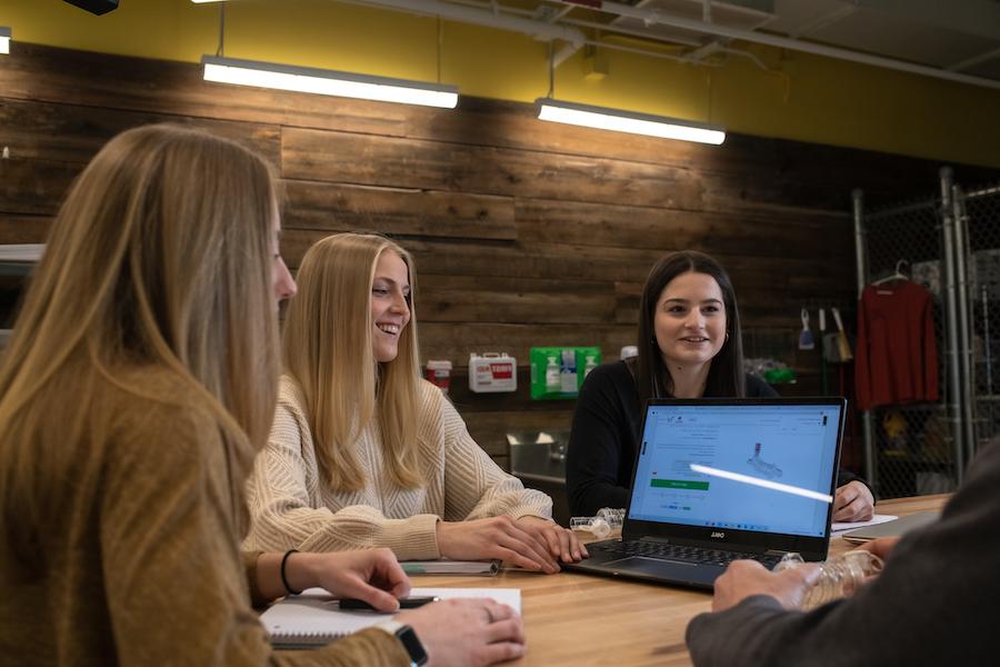 esball国际平台客户端，三个女学生围着桌子和电脑.
